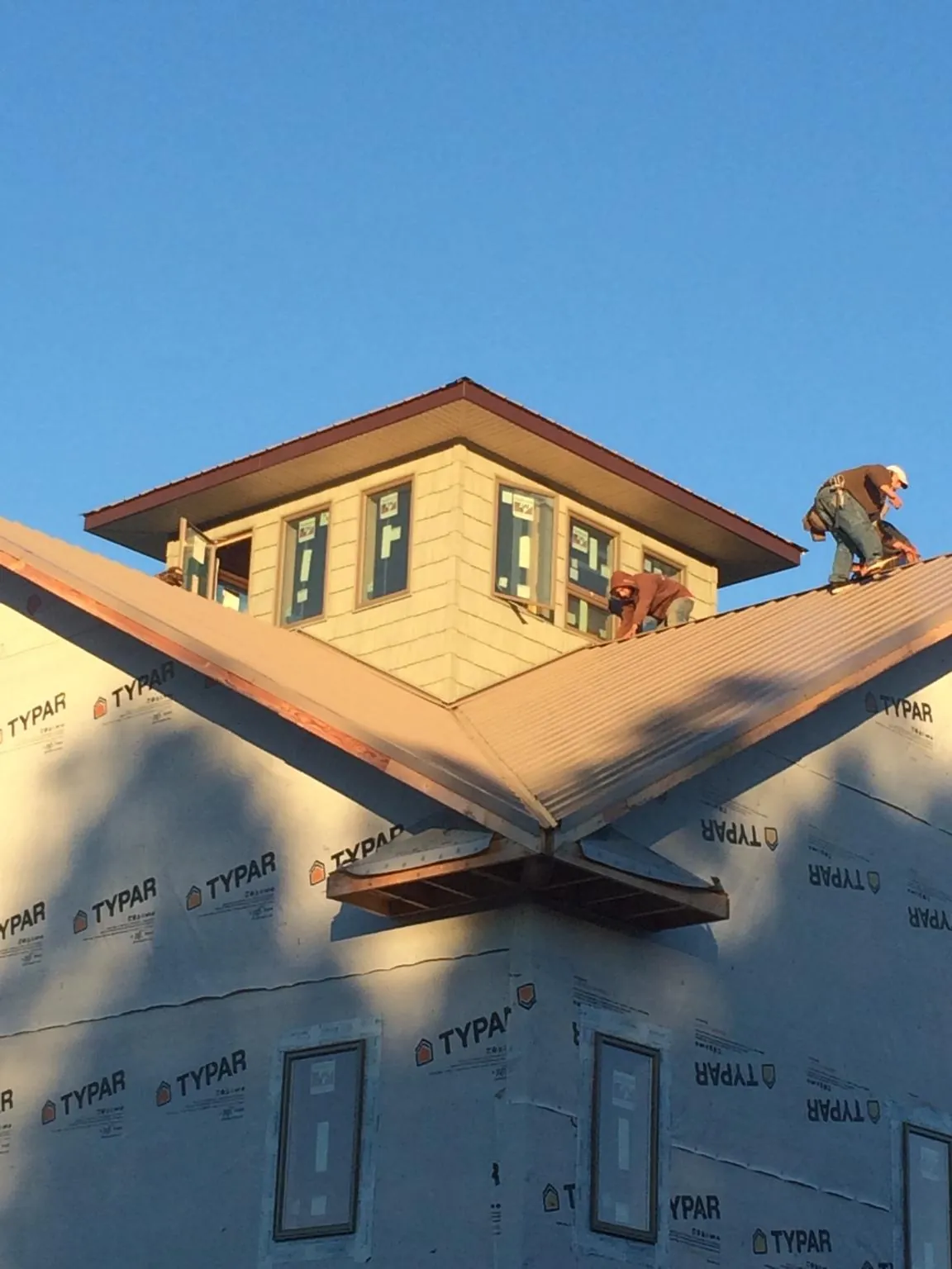 Roofers working around a rooftop cupola on a new metal roof at sunset — Roof Waterproofing in West Salem by Roofing Brothers